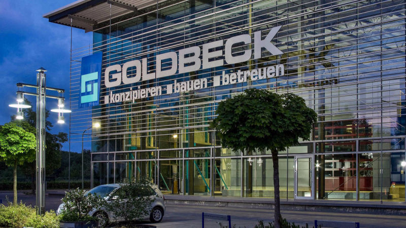 Beleuchtete Glasfassade des Goldbeck-Gebäudes in der Abenddämmerung